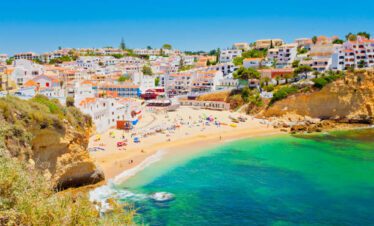 Carvoeiro beach in Algarve tempo with golden cliffs, turquoise water, and hillside whitewashed houses in Portugal